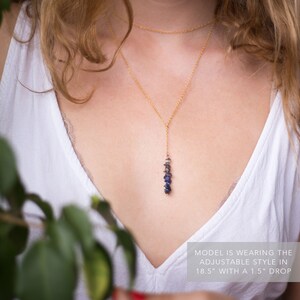 May include: A gold chain necklace with a long, dangling pendant made of small, blue and gray gemstones. The necklace is 18.5 inches long with a 1.5 inch drop. "MODEL IS WEARING THE ADJUSTABLE STYLE IN 18.5" WITH A 1.5" DROP"