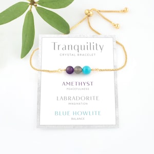 Peut inclure: Bracelet en cristal Tranquilité avec des perles d'améthyste, de labradorite et d'howlite bleue. Le bracelet est doré et possède un fermoir coulissant.