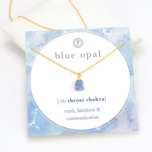 May include: A gold chain necklace with a blue opal pendant. The card reads "blue opal [the throat chakra] truth, kindness & communication".