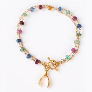 May include: A gold chain bracelet with a multi-colored gemstone charm and a gold horseshoe charm.