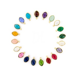 May include: A circle of 18 gemstone charms with gold jump rings. The charms are in a rainbow of colors, including red, orange, yellow, green, blue, purple, and pink.