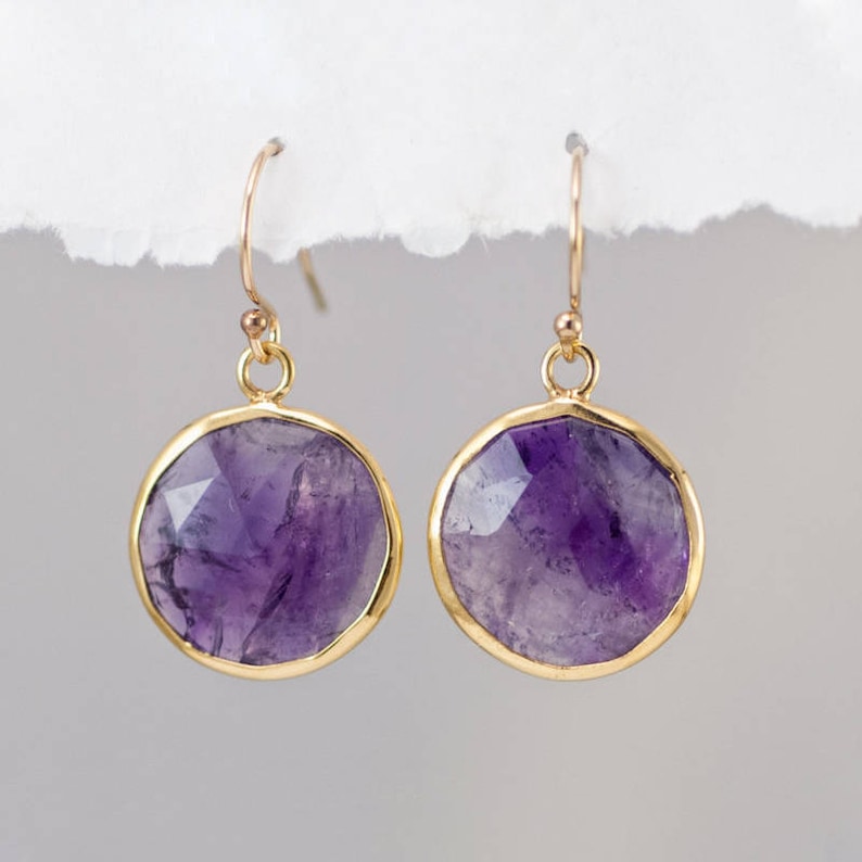 May include: A pair of gold earrings with round, faceted amethyst stones.