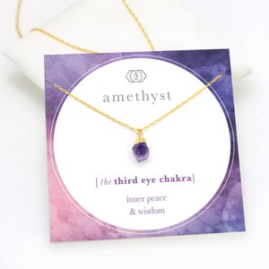 Op de afbeelding: Amethyst ketting met een gouden ketting en een kaart met de tekst "amethyst", "[de derde oog chakra]" en "innerlijke vrede & wijsheid".