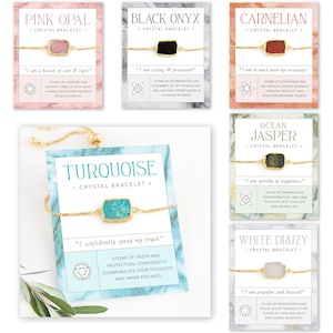 Pu&ograve; includere: Set di dieci braccialetti di cristallo regolabili con catena dorata e pietre di vari colori. Ogni braccialetto presenta un cristallo diverso e un'affermazione corrispondente. I cristalli includono opale rosa, onice nero, corniola, turchese, diaspro oceanico e drusa bianca.