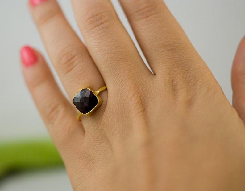K&ouml;nnte beinhalten: Ein goldener Ring mit einem quadratischen schwarzen Edelstein.