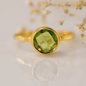 May include: A gold ring with a round green peridot gemstone.
