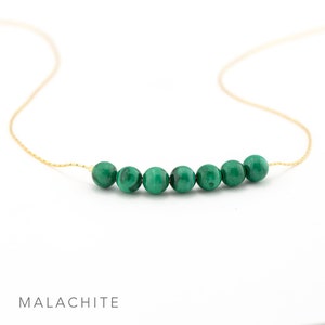 Puede incluir: Un delicado collar de cadena dorada con una fila de seis cuentas redondas de malaquita verde.