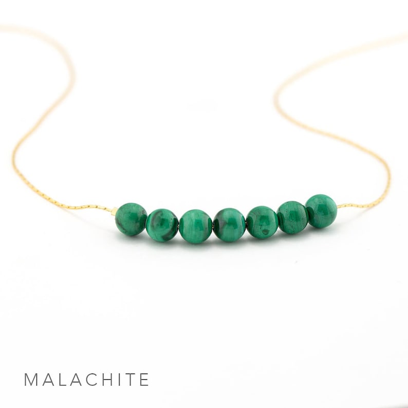 Puede incluir: Un delicado collar de cadena dorada con una fila de seis cuentas redondas de malaquita verde.