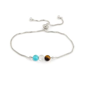 May include: A silver chain bracelet with a turquoise, clear, and tiger's eye bead.