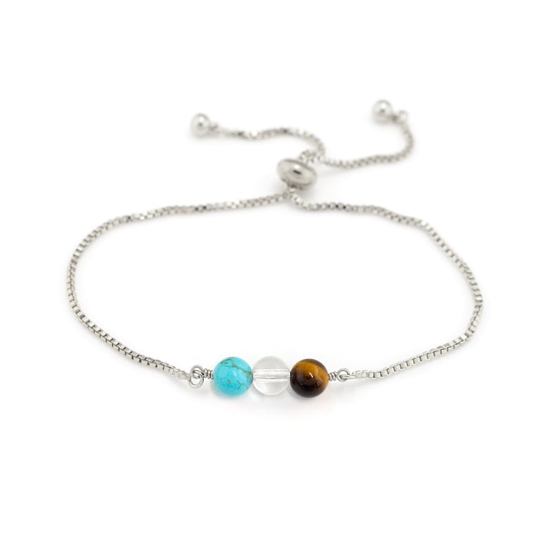 May include: A silver chain bracelet with a turquoise, clear, and tiger's eye bead.