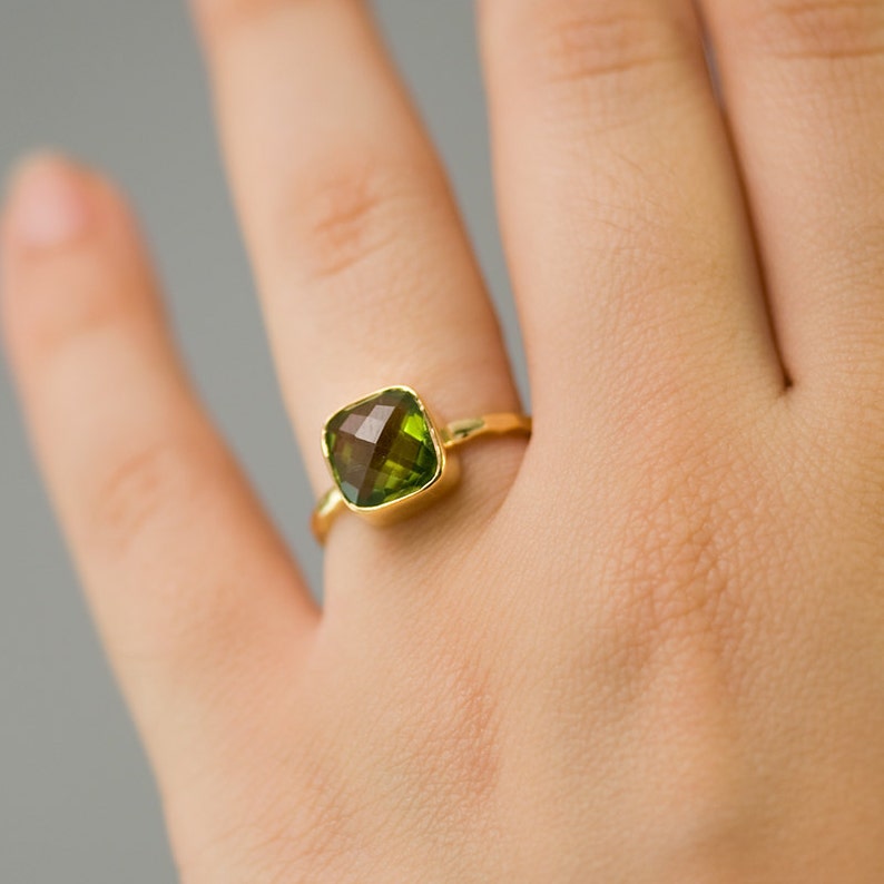 May include: A gold ring with a square green gemstone.