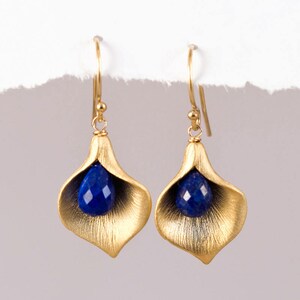 May include: Gold earrings with a blue gemstone in the shape of a flower.