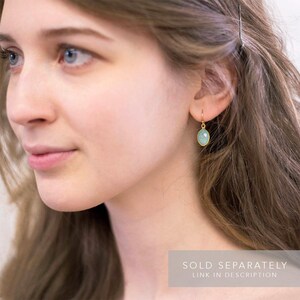 May include: A pair of gold earrings with a light blue gemstone. The earrings are sold separately.  SOLD SEPARATELY LINK IN DESCRIPTION