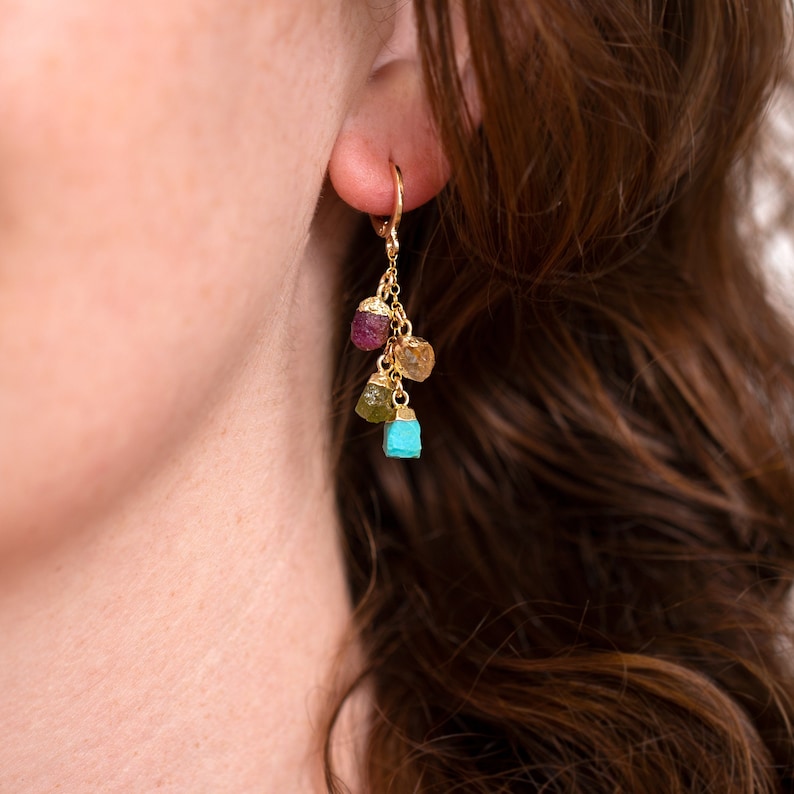 May include: Gold hoop earrings with a dangling cluster of four raw gemstones in shades of turquoise, green, yellow, and pink.