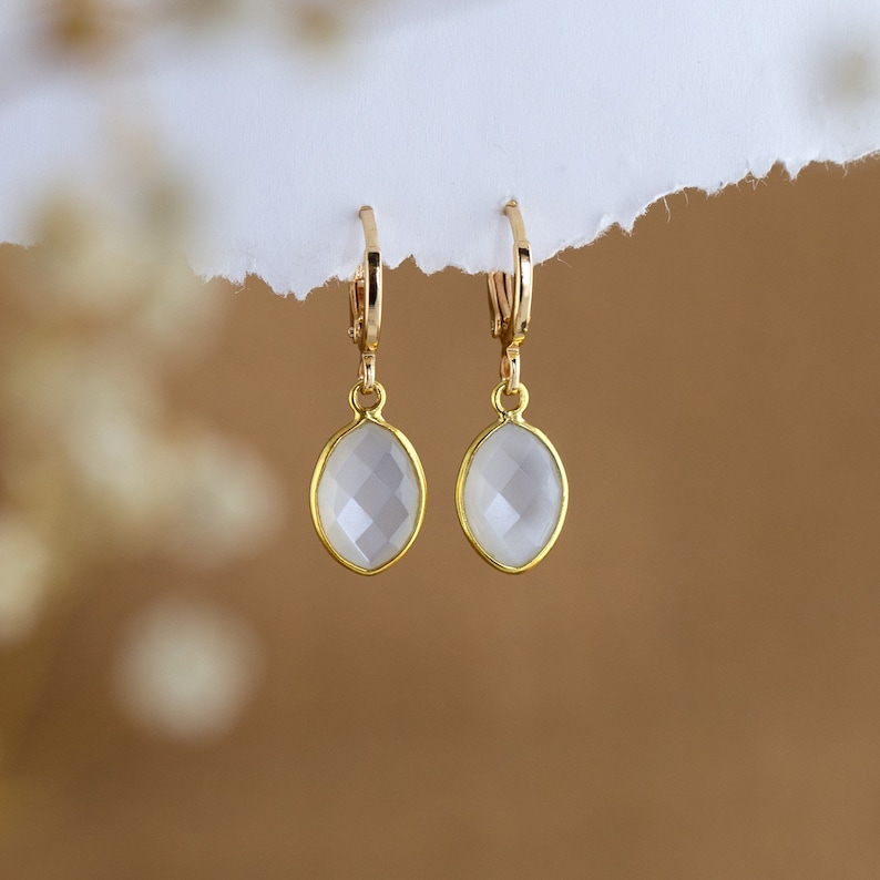 May include: A pair of gold earrings with clear oval-shaped stones.
