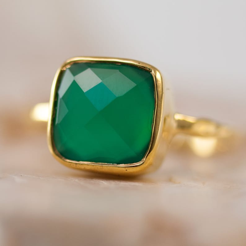 May include: A gold ring with a square green gemstone.