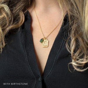 May include: Gold necklace with a Taurus zodiac charm and a green birthstone pendant.