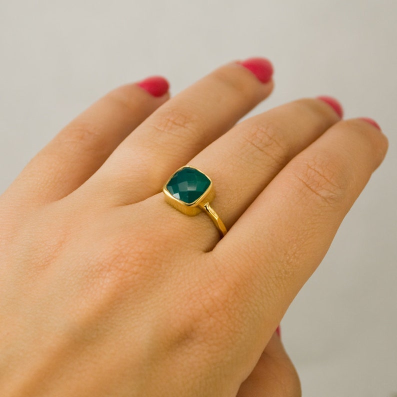 May include: A gold ring with a square green gemstone.