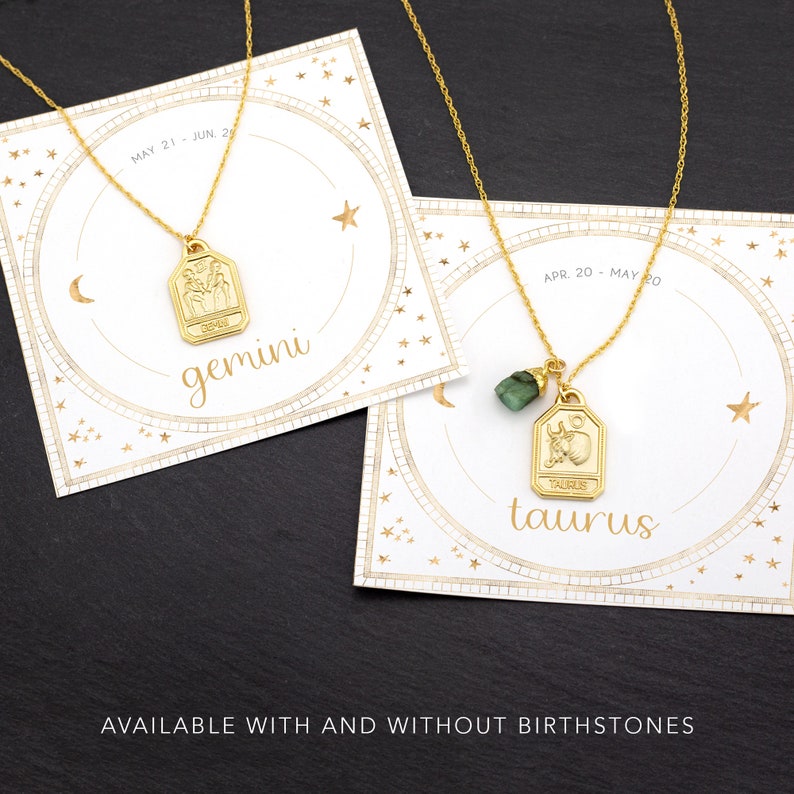 May include: Two gold necklaces with zodiac signs, Gemini and Taurus, on white cards with gold stars. The Taurus necklace has a green gemstone. The text on the cards reads "MAY 21 - JUN. 20", "gemini", "APR. 20 - MAY 20", "taurus", and "AVAILABLE WITH AND WITHOUT BIRTHSTONES".