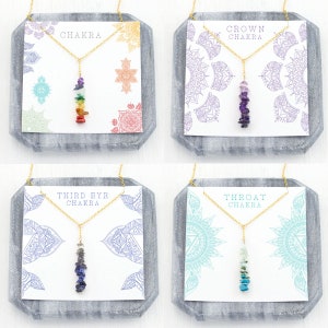 May include: Four gold necklaces with chakra stones. Each necklace is displayed on a card with a mandala design and the name of the chakra. The chakras are: Root, Sacral, Solar Plexus, Heart, Throat, Third Eye, Crown.