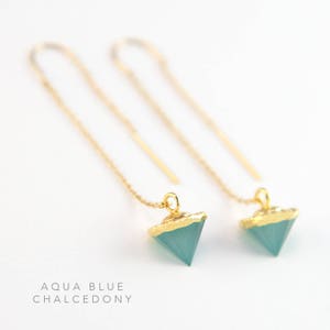 May include: A pair of gold chain earrings with aqua blue chalcedony triangle pendants. The pendants are edged in gold.