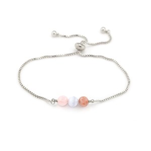 May include: A silver adjustable bracelet with three gemstone beads in pink, pale blue, and peach. The bracelet has a fine chain and a sliding bead closure. The bracelet is designed for a custom fit.