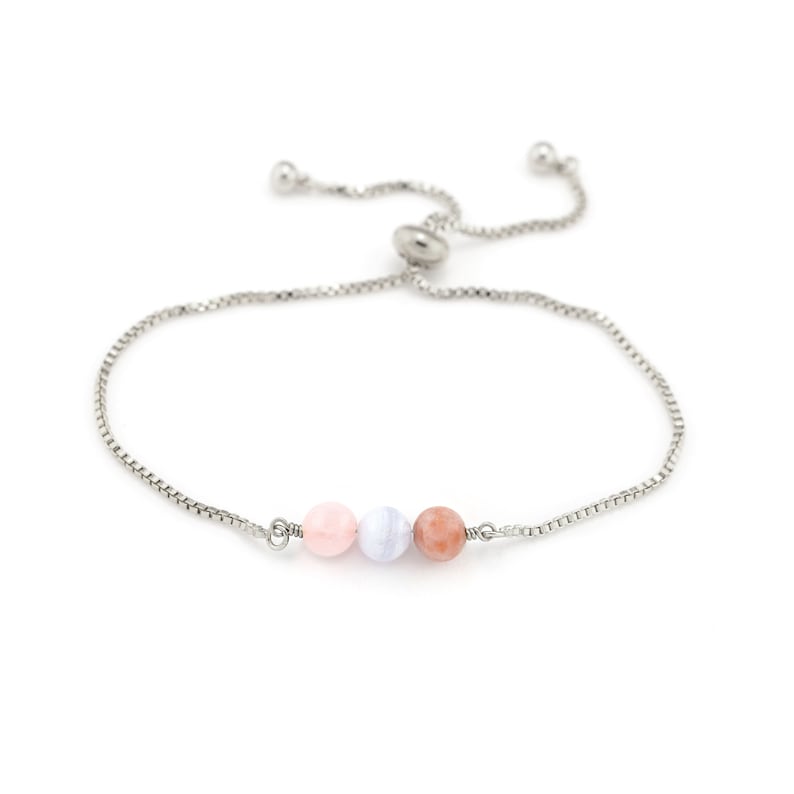 May include: A silver adjustable bracelet with three gemstone beads in pink, pale blue, and peach. The bracelet has a fine chain and a sliding bead closure. The bracelet is designed for a custom fit.