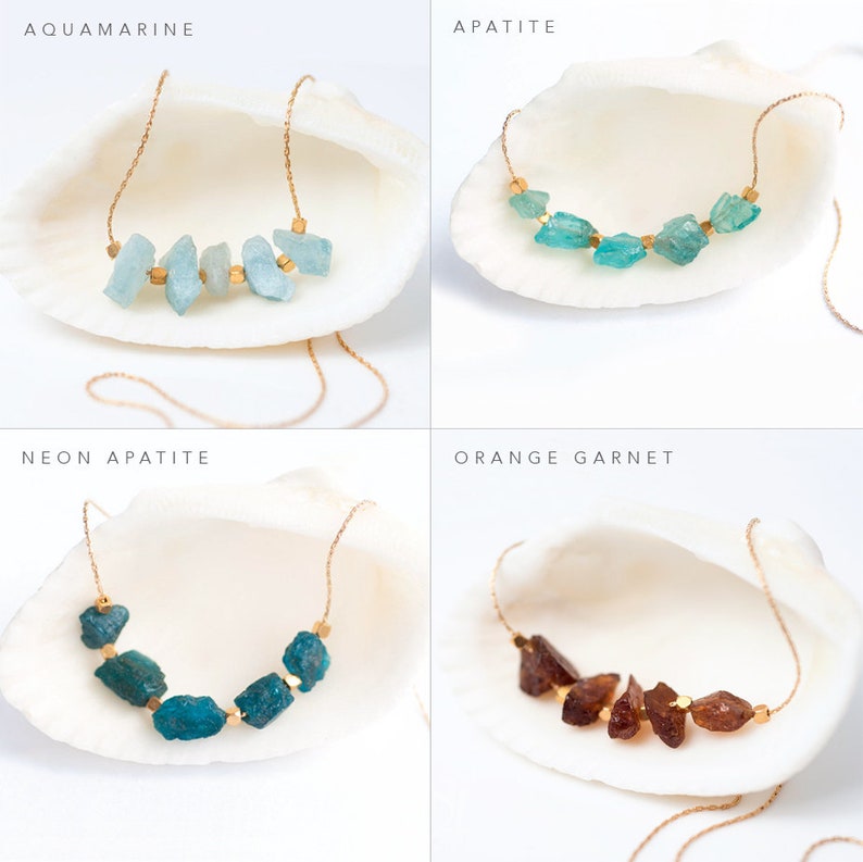 May include: Four necklaces with different colored gemstones on a white seashell background. The necklaces are made with gold chain and feature aquamarine, apatite, neon apatite, and orange garnet stones.