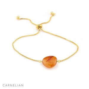 May include: A gold chain bracelet with a carnelian stone pendant. The bracelet is adjustable with a sliding knot.
