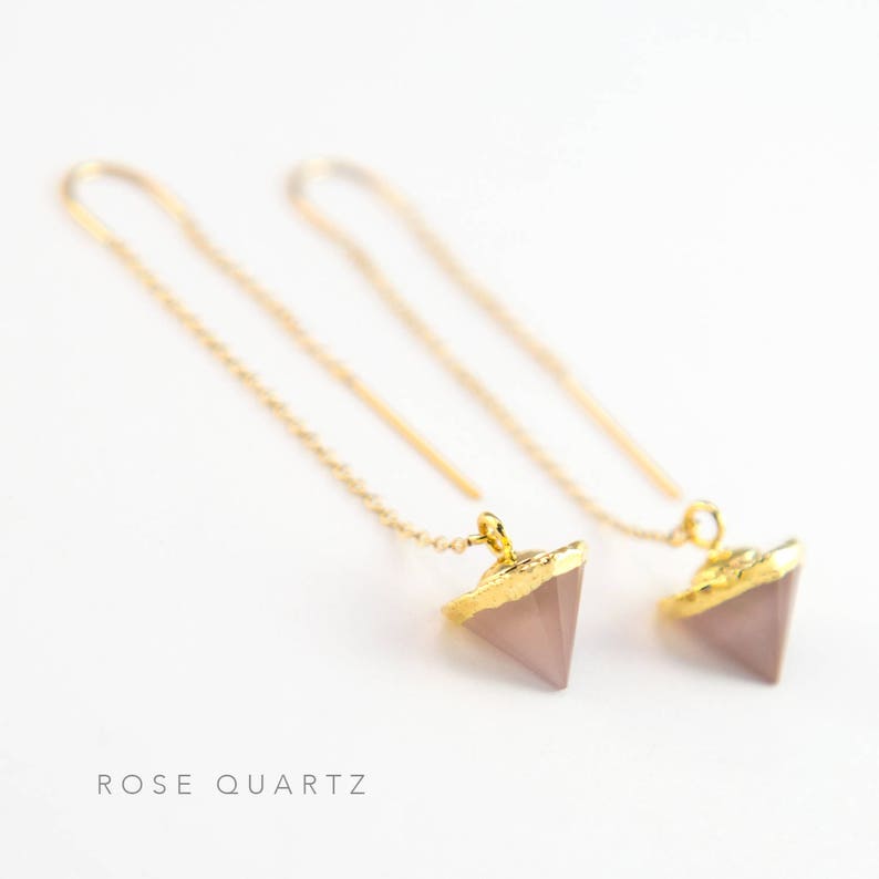 May include: A pair of gold chain earrings with rose quartz triangle pendants. The earrings are delicate and feminine.