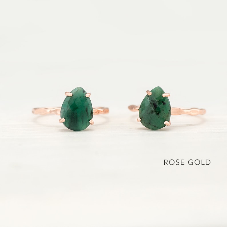 May include: Two rose gold rings with green gemstone pear-shaped settings. The rings have a hammered texture. ROSE GOLD text is visible below the rings.
