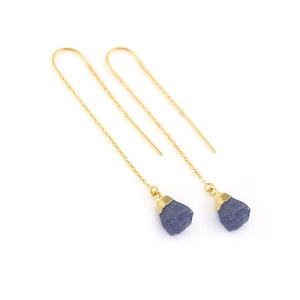 May include: A pair of gold chain earrings with a raw blue sapphire gemstone dangling from each chain.