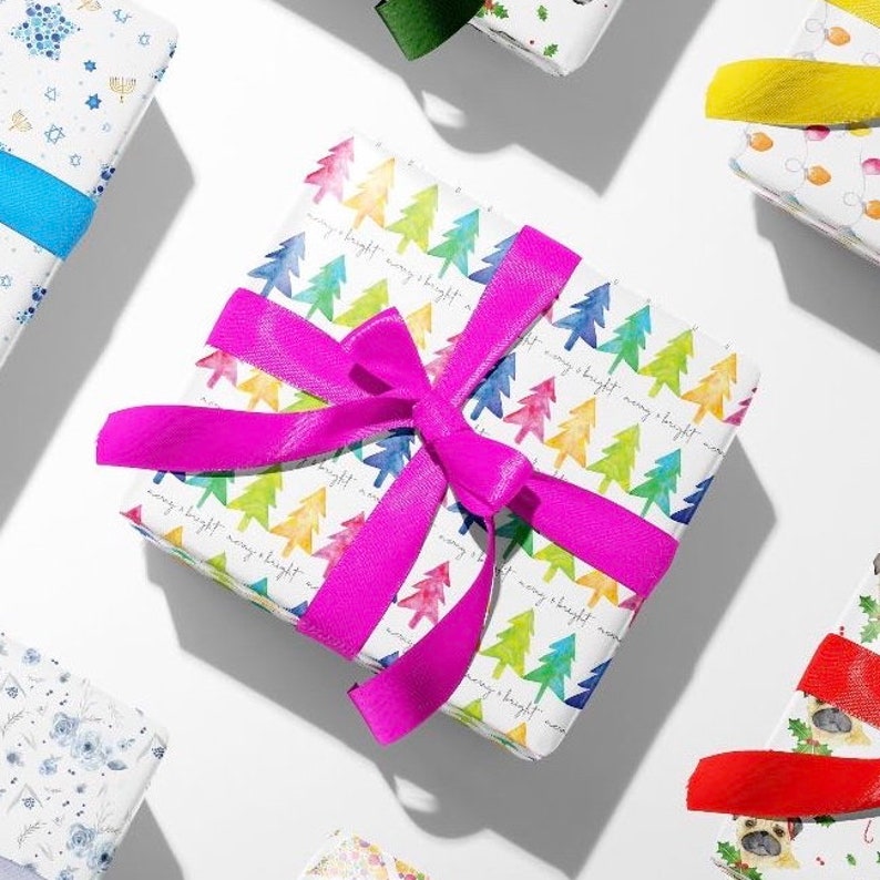 May include: A white gift wrap with a pink ribbon tied in a bow. The wrapping paper has a pattern of colorful watercolor trees and the text "merry & bright" repeated.
