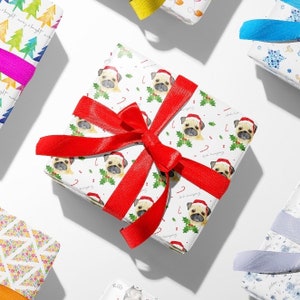 May include: White gift wrap with a repeating pattern of pugs wearing Santa hats and candy canes. A red ribbon is tied around the gift box.