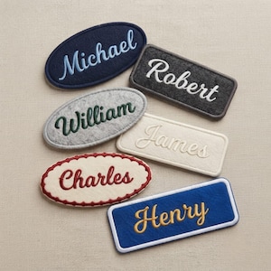 May include: Six felt patches with embroidered names. Oval patches feature Michael in light blue, William in dark green, and Charles in red. Rectangular patches feature Robert in white, James in cream, and Henry in yellow on a blue background.