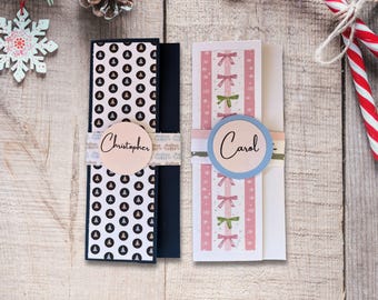May include: Two Christmas-themed gift cards with names. One card has a black and white pattern with the name "Christopher" on a round label. The other card has pink and green bows with the name "Carol".