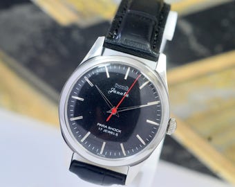 Peut inclure: Une montre-bracelet vintage avec un cadran noir et un boîtier argenté. La montre est dotée d'un bracelet en cuir noir et d'une trotteuse rouge. Le cadran affiche le texte "HMT Janata" et "Para Shock 17 Jewels".