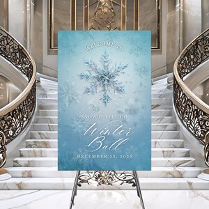 May include: A light blue sign on a metal easel, with the words "Welcome to Winter Ball" and the date "December 22, 2025". The sign features a large snowflake design and smaller snowflakes on a gradient background.