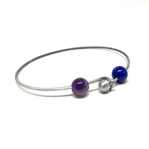 Op de afbeelding: Een zilveren armband met een paarse amethist kraal en een blauwe lapis lazuli kraal.