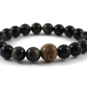 May include: A black and gold beaded bracelet with a wooden bead in the centre.