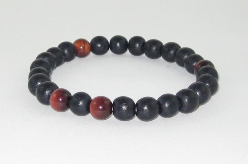 Pu&ograve; includere: Un braccialetto di perline nere e rosse con perline di legno nere alternate a perline di occhio di tigre rosse.