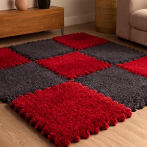 May include: A modular rug made of interlocking squares in red and grey. The rug has a plush, textured surface and is arranged on a wooden floor. The rug's design creates a geometric pattern.