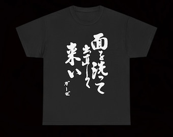 May include: Black t-shirt with white Japanese calligraphy. The text appears to read "Wash your face with gauze." The shirt is a crew neck style and has short sleeves. The text is written in a brush stroke style.