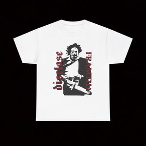 May include: White t-shirt with a black and red graphic of a figure holding a chainsaw. The words "Framing" and "dispose" are printed in red on the shirt. The design is a stylized illustration.