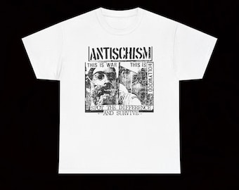 May include: White t-shirt with a black graphic design. The design includes the word "ANTISCHISM" above two black and white portraits. Below the portraits is the text "SPOT THE DIFFERENCE AND SURVIVE".