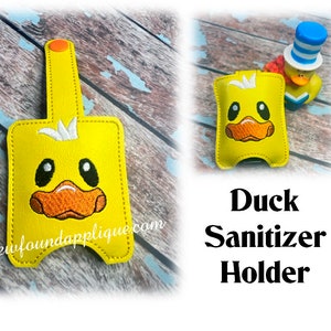 May include: Yellow duck-shaped hand sanitizer holder with a white beak and black eyes. The holder has a loop at the top for attaching to a bag or keychain. The text "Newfoundapplique.com" is visible on the bottom of the holder.  Duck Sanitizer Holder.