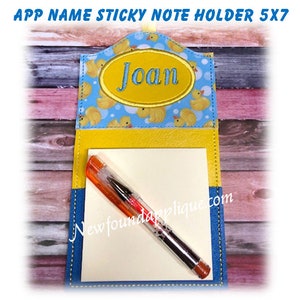 May include: A blue, yellow, and white sticky note holder with a duck pattern and the name "Joan" embroidered on it. Includes a notepad and a pen. The text "APP NAME STICKY NOTE HOLDER 5X7" is at the top, and "newfoundapplique.com" is at the bottom.