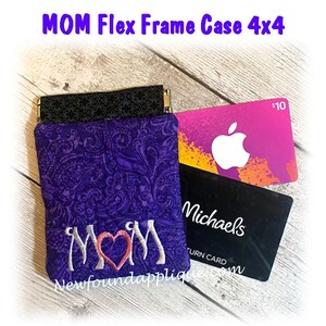 May include: A purple fabric flex frame case with a paisley design, embroidered with the word "MOM" and a heart. The case is shown with a black patterned top and two gift cards, one from Apple and one from Michaels.