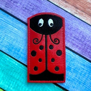 May include: A red ladybug-shaped applique with black spots and a black head. The applique has white eyes and is made of a smooth material. The ladybug design is a whimsical and playful element.