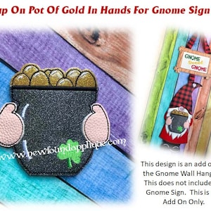 Könnte beinhalten: Eine Filzapplikation eines Topfes voller Gold, der von Händen gehalten wird. Der Topf ist schwarz mit goldenem Glitzer und einem Kleeblatt. Die Hände sind rosa. Der Text "GNOME Sweet GNOME" ist im Hintergrund sichtbar.